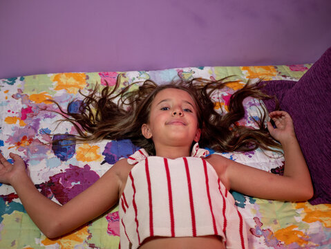 Cute little Caucasian girl lying down on her bed