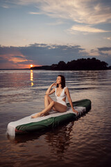 A beautiful girl swims on a sup board. Summer sports and outdoor activities. Free time outdoors....