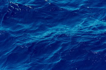 Fototapeta na wymiar splashes and foam in the blue sea in Greece