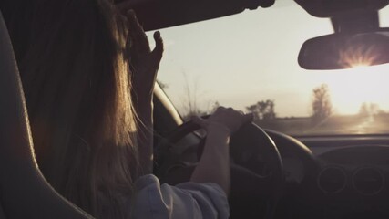 A young girl driving a convertible starts moving. The beginning of the journey. Woman driving a car. Holds the steering wheel with his hands. Roadtrip on the highway. Hair in the wind in slow motion.