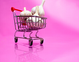 A small cart from the store with three heads of garlic. 