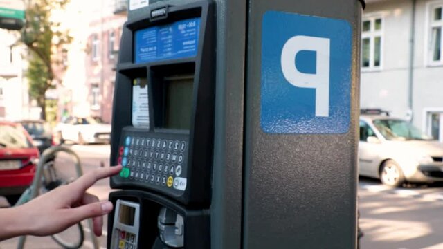 The girl pays in the parking lot for paid parking in the city