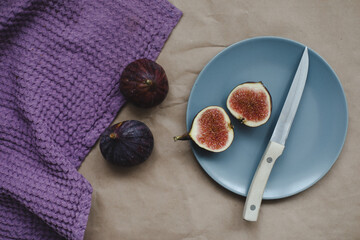 still life with ripe fresh figs with a knife and purple textiles on a table top view