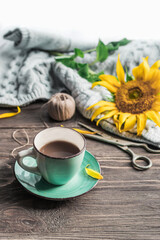 A cup of coffee on a wooden table, an open book and a warm sweater on the background of a bouquet of flowers. Still life concept. Cozy morning.
