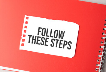 The word Follow these steps on torn paper on red notepad,.