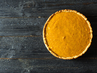 Autumn traditional pumpkin pie top view on a wooden black table with copy space
