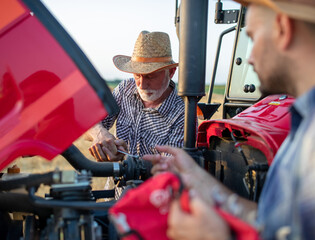 Farmers working with wrench on broken tractor in field