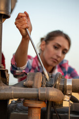 Woman repairing tractor with screwdriver in field