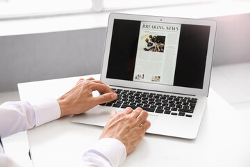 Young businessman reading newspaper online in office