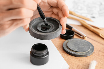 Young male calligrapher with ink at home, closeup