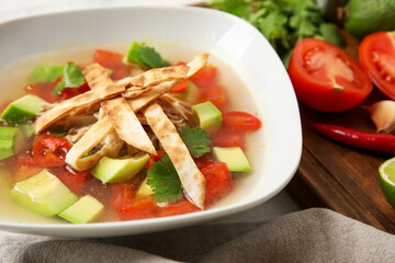 Bowl of tasty Sopa de Lima soup and ingredients on table
