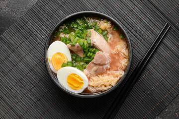 Tasty Chinese soup with chicken in bowl on dark background