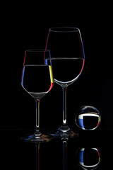 Two glasses and a glass ball on a black background