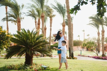 Happy loving mother and son playing and hugging. Family walk near palms. Turkey beach hotel. Summer time together, sun light. Happy Mothers day.