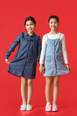Cute little sisters on color background