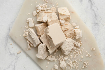 Board with fresh yeast on light background