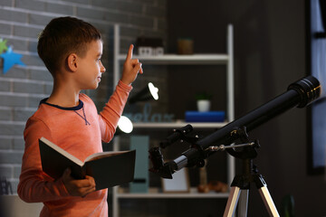 Little boy with book and telescope at home