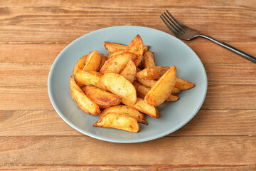 Plate with tasty baked potato on wooden background