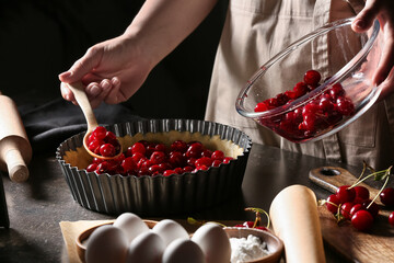 Woman cooking cherry pie at table