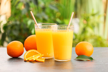 Glasses of tasty orange juice on table outdoors