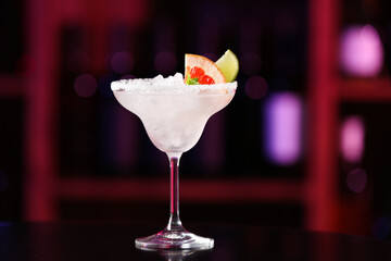 Glass of tasty grapefruit margarita on table in bar
