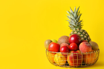 Basket with fresh fruits on color background