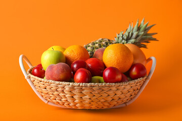 Basket with fresh fruits on color background