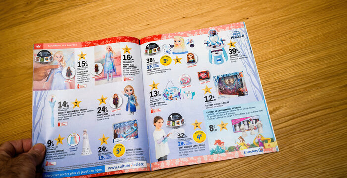 Paris, France - May 19, 2020: Pov male hand reading latest catalogue brochure advertising flyer with multiple toys for kids childrens - puppets processes etc
