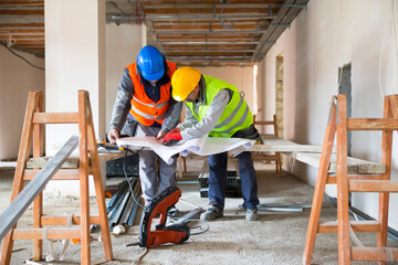 Team of architects and engineers in group on construciton site check documents.