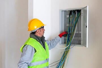 The electrician holding the colorful cables in the electrical panel 