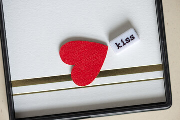 the word "kiss" and a red heart on fancy paper