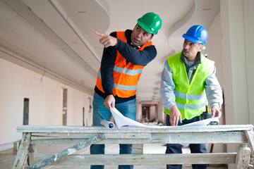 Portrait  of an architect showing the walls to the worker for painting.