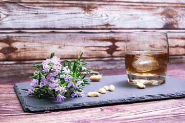 Obraz na płótnie Canvas glass of whiskey with walnuts and rosemary flower