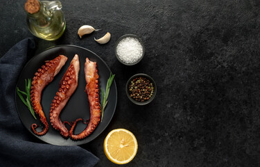 grilled octopus tentacles, on a dark plate on a stone background with copy space for your text © александр таланцев