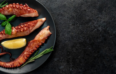 grilled octopus tentacles, on a dark plate on a stone background with copy space for your text © александр таланцев