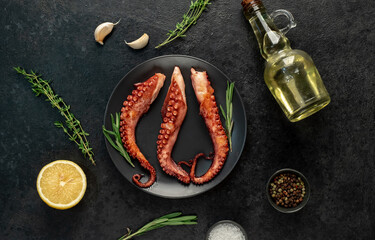 grilled octopus tentacles, on a dark plate on a stone background © александр таланцев