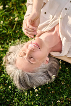 Woman with flower in hand lying on lawn