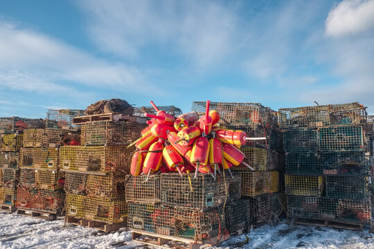 Colorful lobster traps and brightly painted lobster floats sitting on a New England Boat dock in winter