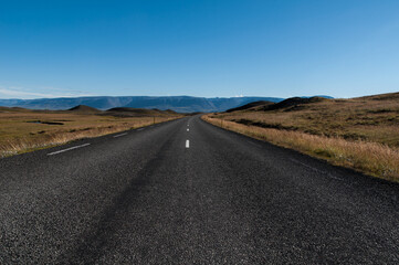 Empty asphalt highway through Iceland under the blue clear sky