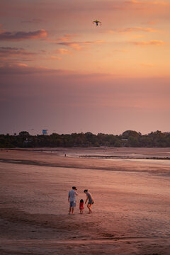 Family flying a kite at the beach at sunset in Darwin, Northern Territory, Australia
