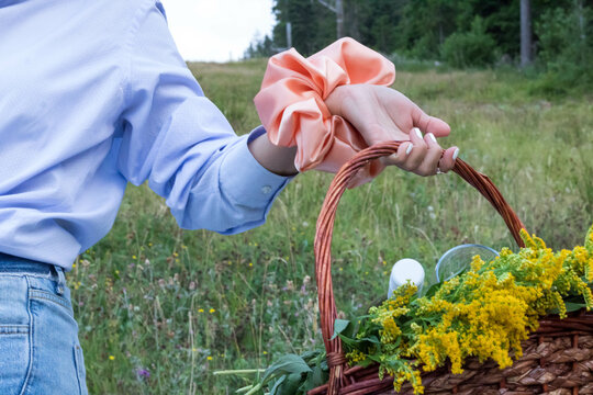 View of a female carrying a basket of flowers with a beautiful scrunchy on her hand in the filed