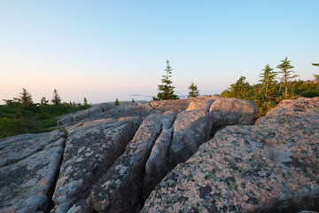 First Rays of Sunlight strike the Crevasses in the Pink Granite Rocks at the top of Cadillac Mountain In Acadia National Park