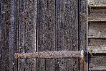 Rusting iron hinges on an old rotting wooden farm door