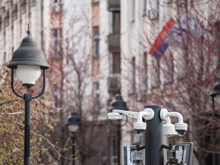 Selective blur on dome cctv cameras seen from afar in front of an old street in an urban European...