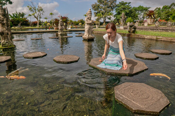 バリ島お伝統的な宮殿Tirta Ganggaで鯉にえさをあげる女性