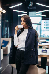Fashion model with coffee cup in restaurant.