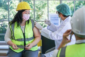 Worker woman sitting to getting covid vaccine, with nurse injecting vaccine to get immunity for...