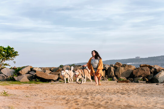 one girl walking with two husky dogs at the beach