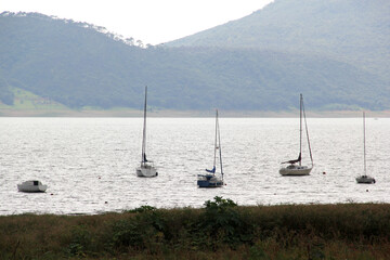 Port of small and large sailboats parked and sailing on the lake of Valle de Bravo in Mexico at...
