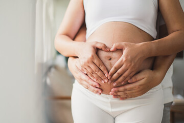 Close up pregnant couple woman and husband making heart on belly
